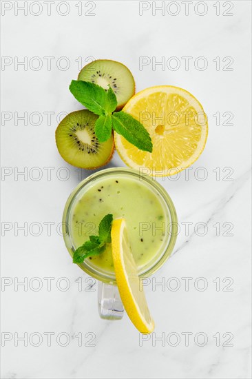Overhead view of kiwi and lemon smoothie with mint on marble background