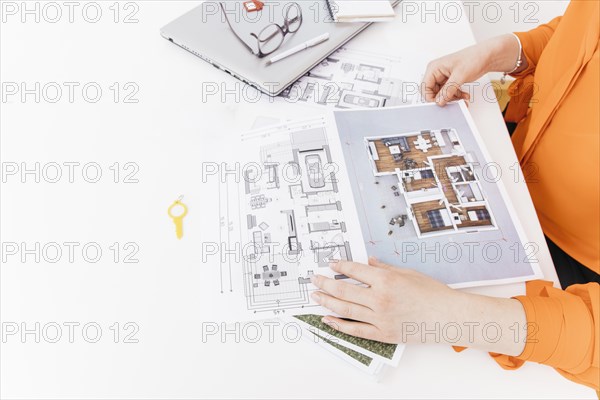 Elevated view of female hand holding blueprint on white desk