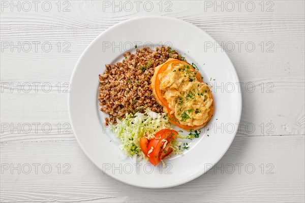 Top view of plate of chopped meat backed with tomato with buckwheat and cabbage salad