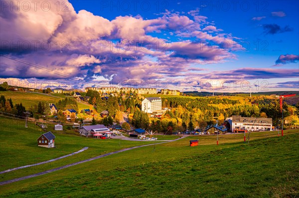 View to the skiing area in Oberwiesenthal in the Ore Mountains with the Fichtelberg suspension railway in autumn at sunset