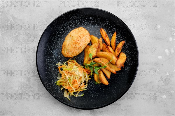 Kiev cutlet stuffed with cheese and butter served with fried potato wedges and pickled cabbage