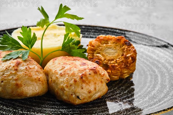 Close up view of ground meat cutlet with mashed potato and grilled corn slices