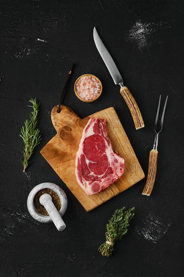 Overhead view of raw strip steak bone in on dark background