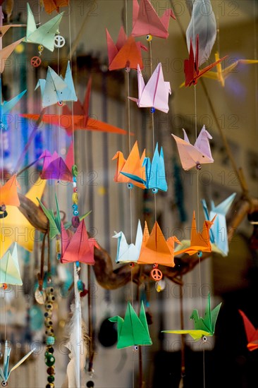 Colorful paper origami birds tied to strings hanging in air
