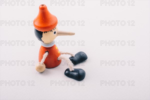 Wooden pinocchio doll with his long nose on a white background