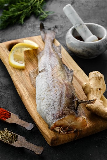 Raw fresh frozen pollock carcass with spices on cutting board