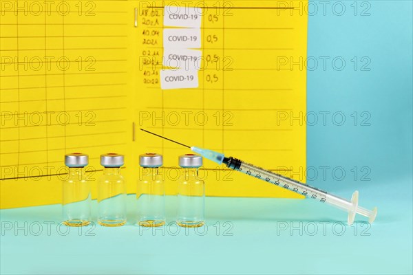 Corona booster vaccine concept with 4 vials with syringes and certificate of vaccination in background with copy space