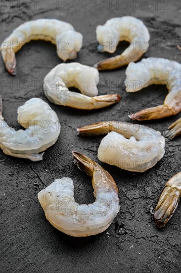 Peeled fresh raw white prawns on wooden background