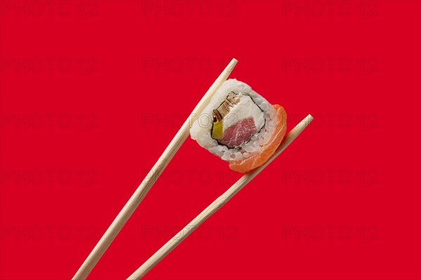 Holding roll with salmon and tuna with chopsticks