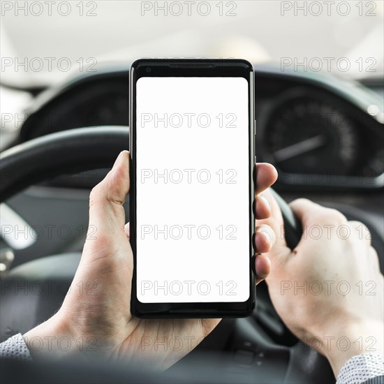 Close up man s hand driving car showing blank white screen mobile phone