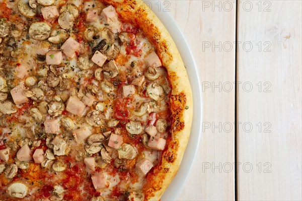 Top view of pizza with ham and champignon on wooden table