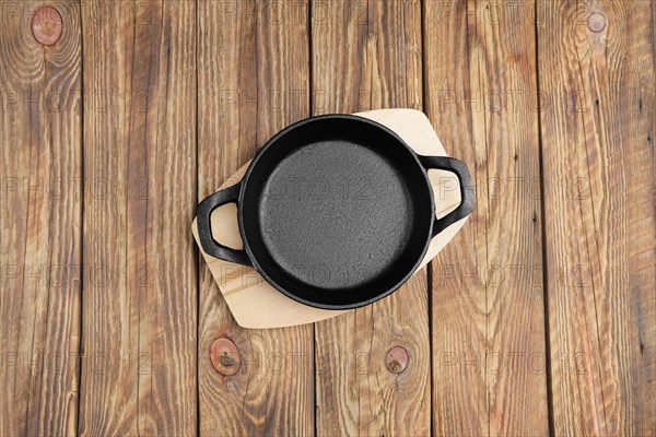 Top view of cast-iron skillet with two handles on wooden table