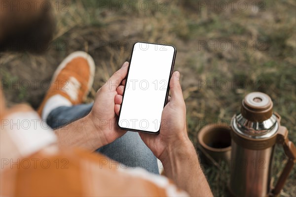 Man holding smartphone while camping outdoors