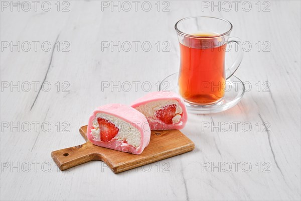 Sweet dessert mochi with strawberry cut on half with fruit tea