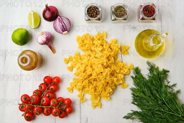 Top view of raw farfalle pasta with spice and herbs on wooden background