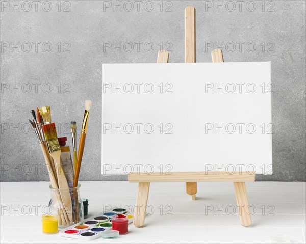 Canvas easel glass filled with paint brushes