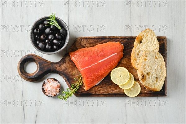 Top view of piece of fresh salmon tail fillet with ciabatta and spicy herb sauce