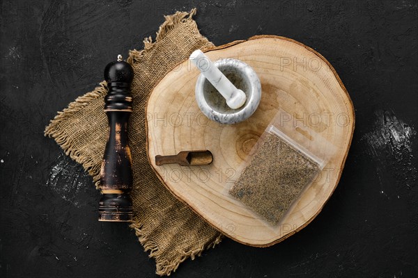 Wooden cross section with mustard in plastic package and stone mortar and mill