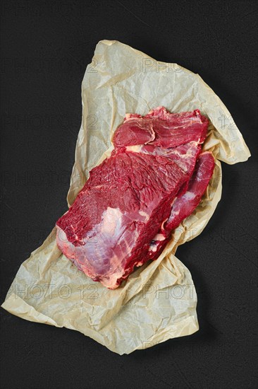 Overhead view of raw fresh beef neck on wrapping paper
