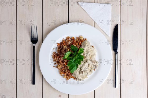 Top view of beef stroganoff with creamy onion sauce and buckwheat with fried mushrooms on served table