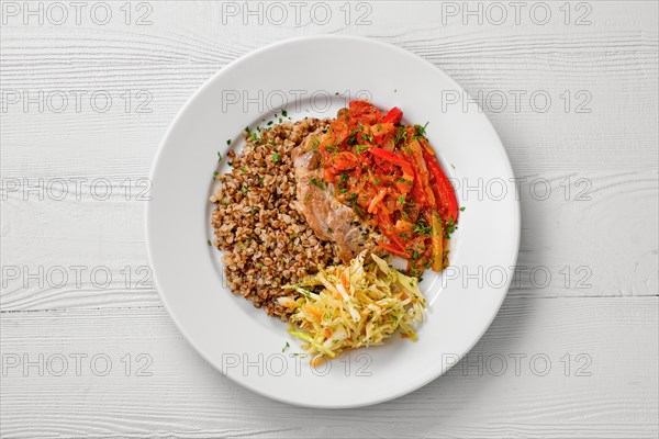 Top view of plate with chopped meat backed with bell pepper with buckwheat and cabbage salad