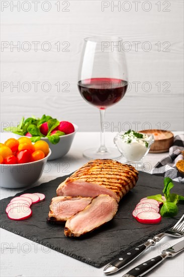 Grilled beef steak medium rare on stone board with fresh vegetables and glass of red wine