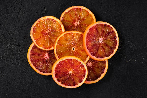 Overhead view of slices of blood orange on black background