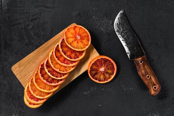 Overhead view of slices of blood orange on black background