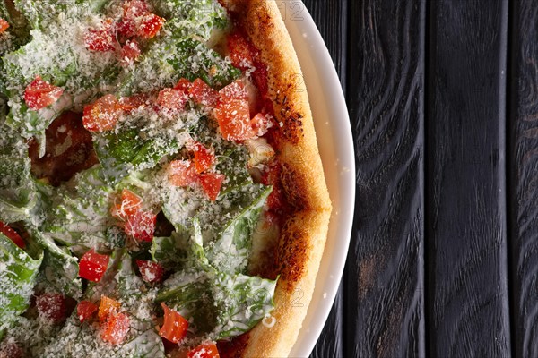 Top view of pizza with ham and green salad leaves arugula