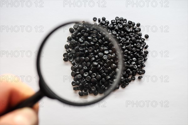 Photo of a raw plastic with a magnifying glass in hand on a white background Polipropylene