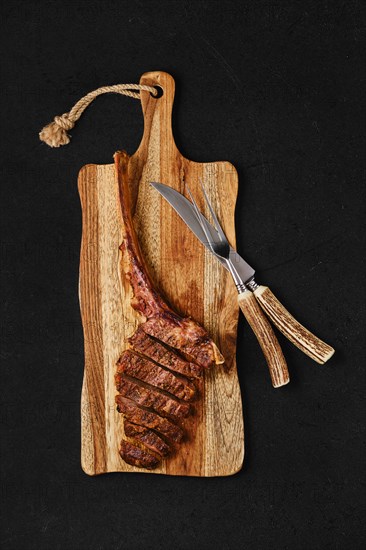 Tomahawk steak cut on slices on wooden board