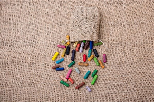 Crayons of various color out of a sack on a canvas