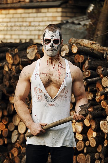 Male daemon with axe near firewood placing. Face painting art