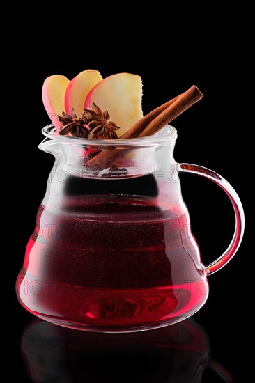 Jug with apple and cranberry tea isolated on black background