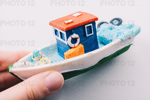 Little colorful model fishing boat in hand on white
