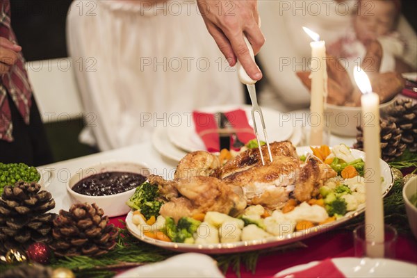 Hand holding turkey with fork christmas table