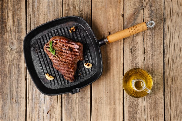 Overhead view of chuck eye steak fried on cast iron grill pan