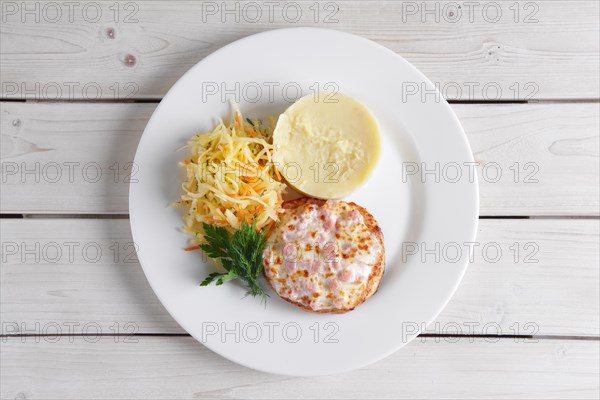 Fish cutlet with ham and melted cheese topping served with pickled cabbage and mashed potato