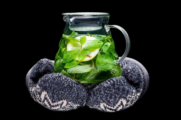 Hands in warm gloves holding pot of herbal tea