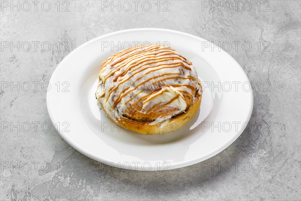 Fresh cinnamon bun with sugar icing and caramel
