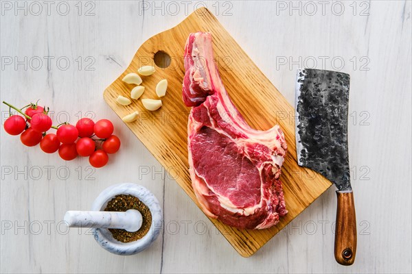 Beef ribeye steak bone-in with spice on wooden cutting board