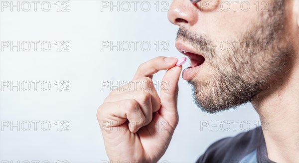 Close-up of a man taking an aspirin. Person taking a pill isolated