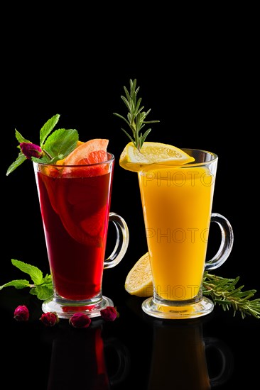 Two glasses of rose tea and lemon tea with ginger and rosemary isoalted on black.