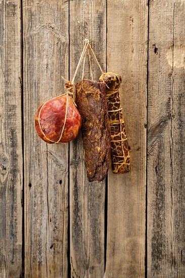 Assortment of dried meat and sausages hanging on a barn wall