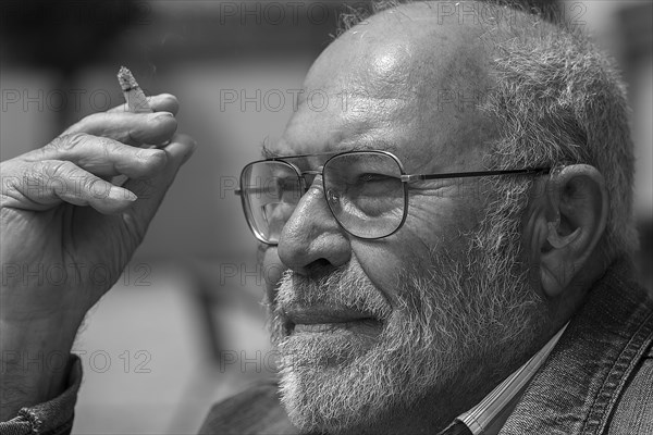 Portrait of a smoking gentleman with beard and hearing aid in ear