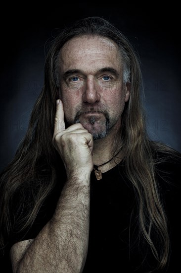 Man with long hair and hand with outstretched index finger on chin