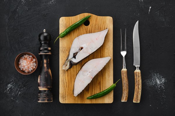 Top view of raw fresh halibut steak on wooden cutting board with spices