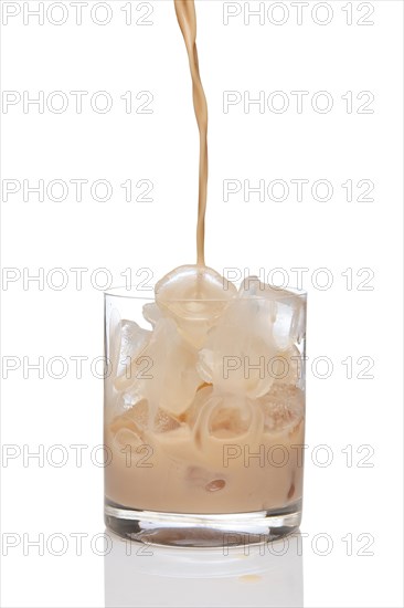 Irish creme liqueur pouring in a glass full of ice