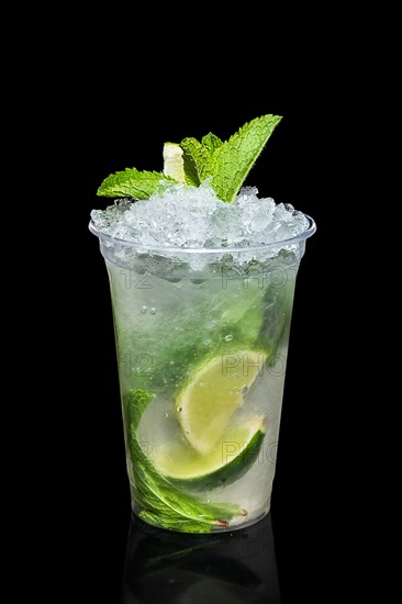 Cold lime and mint cocktail with a sparkling wine with ice in take away glass isolated on black