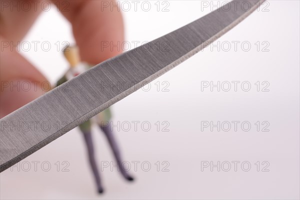 Hand holding a pocket knife near a human figure on a white background